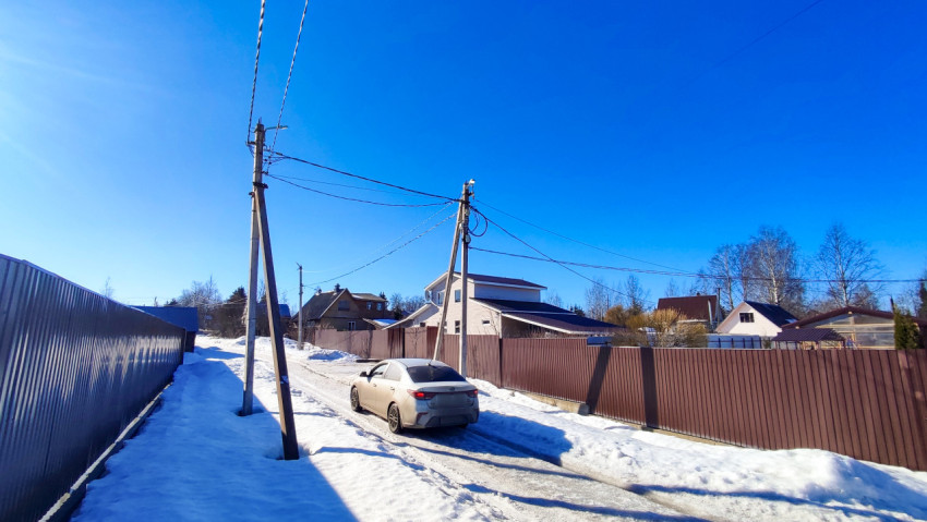 Легковой автомобиль на загородной улице с электролиниями зимой