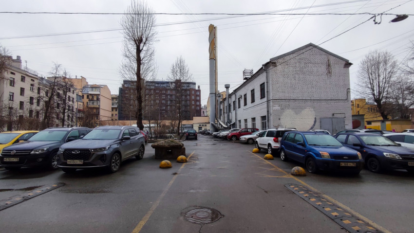 Парковка у промышленного здания с дымовой трубой