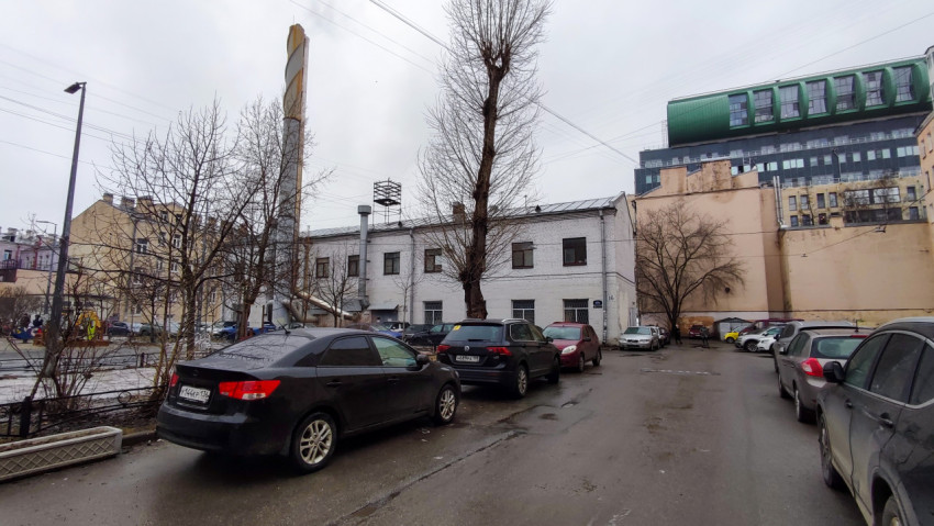 Белое кирпичное здание с парковкой и промышленной трубой