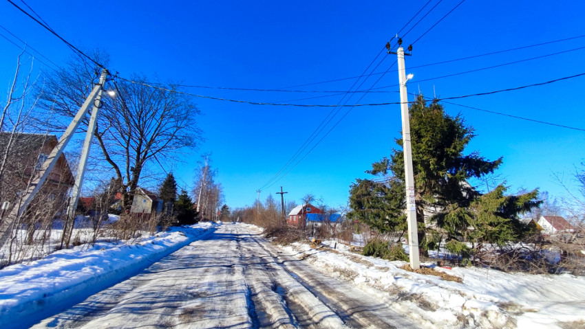 Заснежённая дорога с хвойными насаждениями и линиями электропередачи