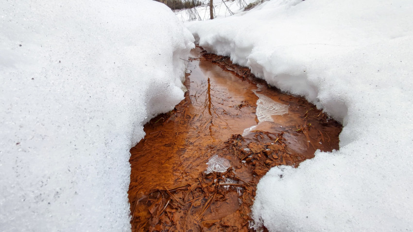 Небольшой ручей талой воды среди сугробов
