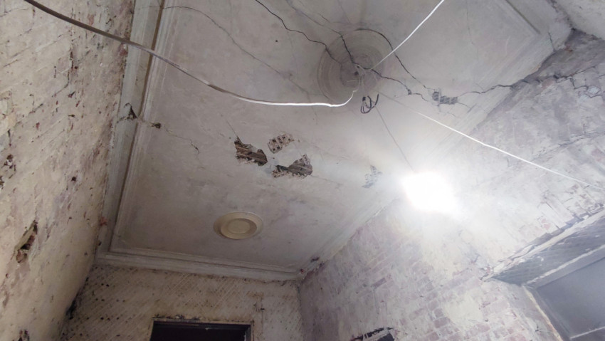 Потолок старого здания с трещинами и следами повреждений