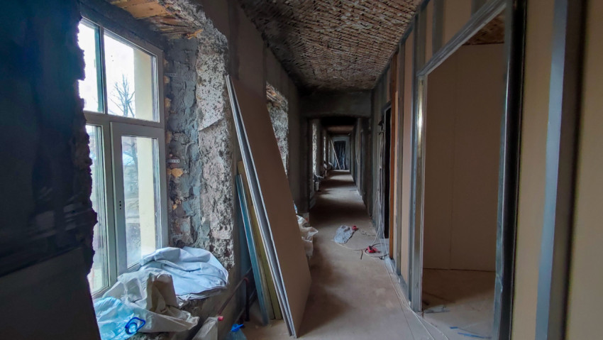 Длинный коридор старого здания с частично открытой кладкой