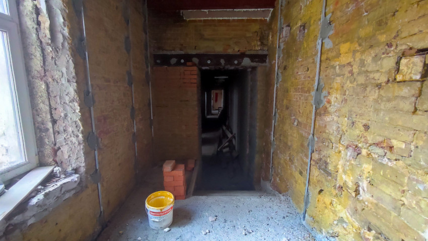 Коридор с кирпичными стенами и строительными материалами