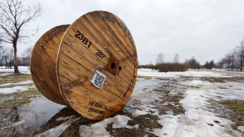 Деревянный барабан с кабелем на фоне заснеженного поля