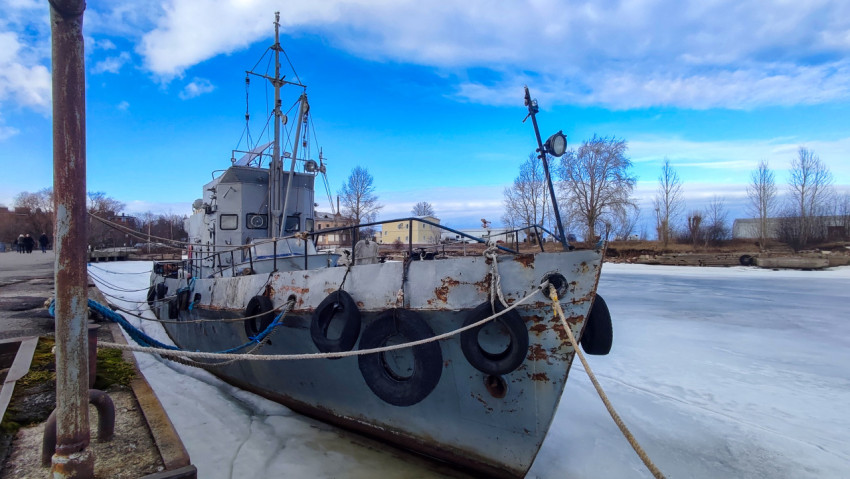 Старое судно у берега на фоне промерзшего залива