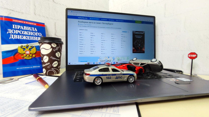 Ноутбук и модельные машины на фоне книги ПДД и знака STOP
