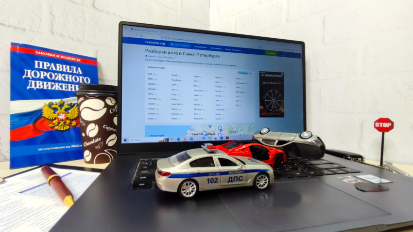 Ноутбук с моделями автомобилей и книгой ПДД на столе