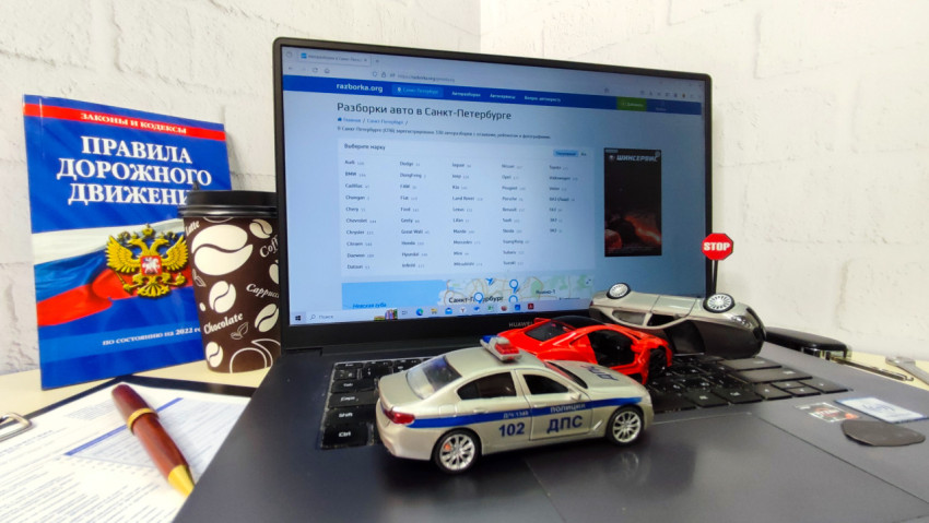 Ноутбук с модельными автомобилями и книгой ПДД рядом