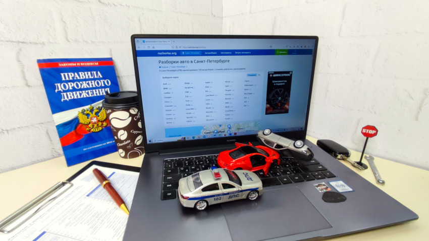 Ноутбук с модельными автомобилями и книгой ПДД в офисе