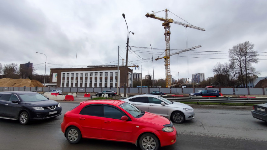 Дорожный трафик у строительной площадки с башенными кранами