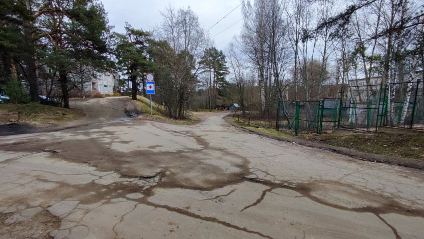 Разбитая дорога у жилых домов и лесополосы в пригороде