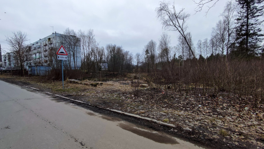 Пятиэтажный жилой дом и пустырь с предупреждающим дорожным знаком