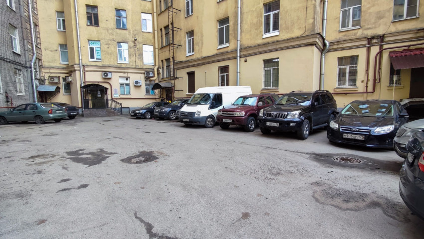 Автомобили на парковке во внутреннем дворе старого жилого дома