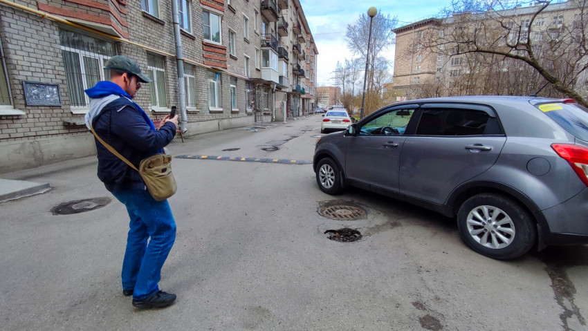 Дворовая дорога с автомобилями и прохожим возле кирпичного дома