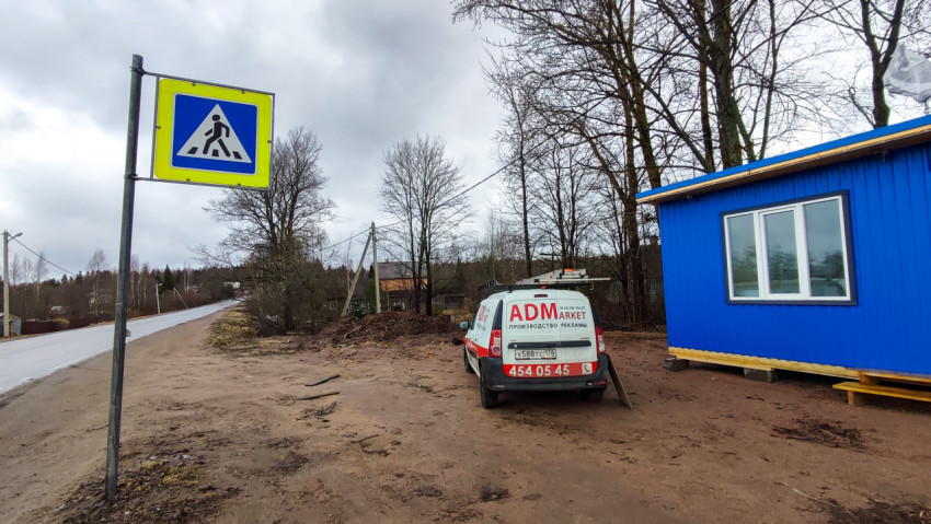 Знак пешеходного перехода и сервисный автомобиль у модульного здания