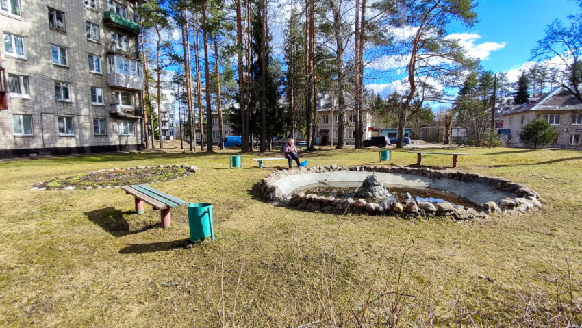 Фонтан и скамейки во дворе среди многоэтажных жилых домов