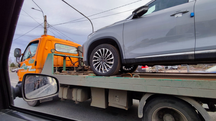 Эвакуатор с легковым автомобилем на платформе в городской среде