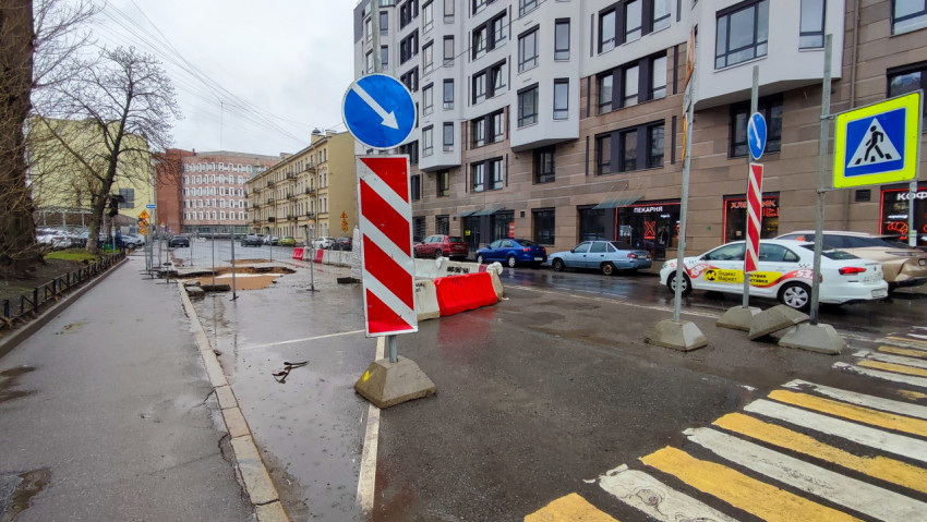 Перекрытый участок дороги и временные ограждения у жилого здания