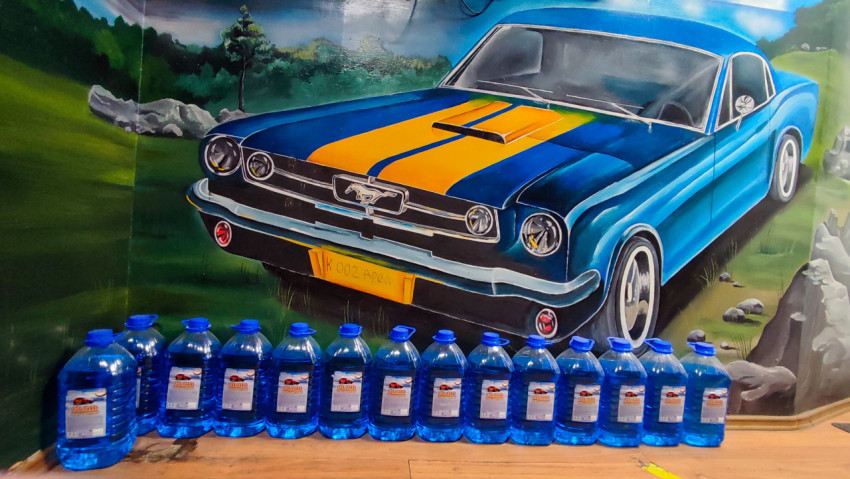Ряд канистр с технической жидкостью перед настенной росписью автомобиля