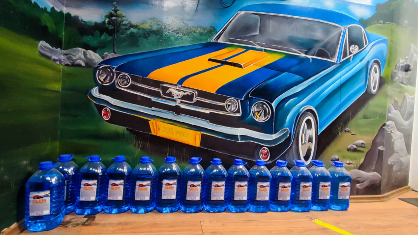 Канистры стеклоомывающей жидкости на фоне настенной росписи автомобиля