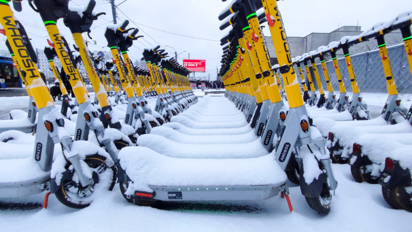Парковка электросамокатов под снегом рядом с трамвайной линией