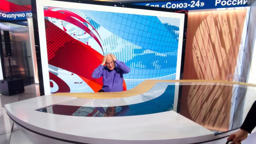 Посетитель за новостным столом на фоне крупного LED-экрана с графикой форума