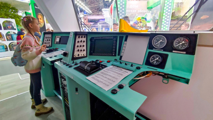 Посетитель стенда у пульта машиниста локомотива