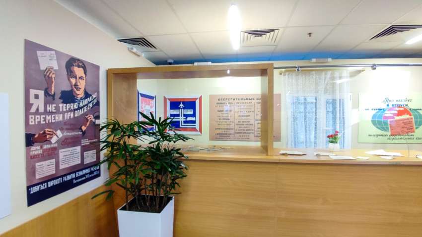 Зал с советскими плакатами и стойкой обслуживания в реконструкции сберкассы