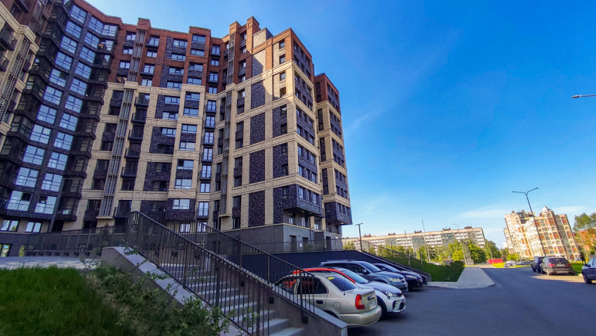 Высотные жилые здания с парковкой на фоне чистого неба