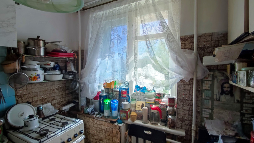 Кухня квартиры с посудой, продуктами и кружевной занавеской на окне