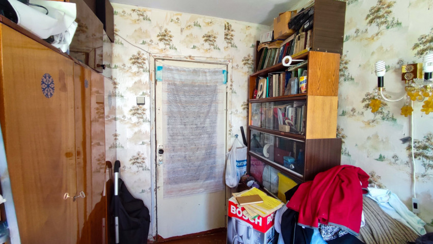 Участок комнаты с книжным шкафом, дверью и бытовыми вещами