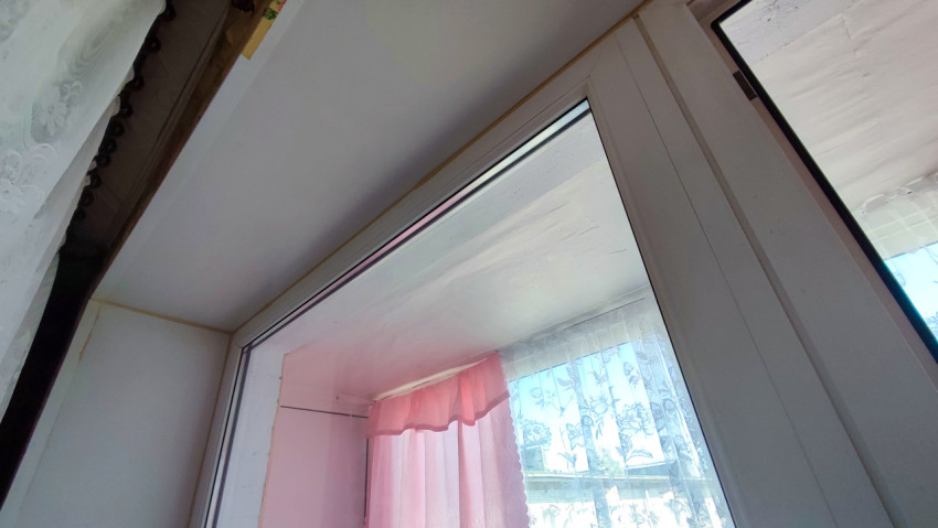 Пластиковое окно с тюлевыми шторами и потолочной отделкой