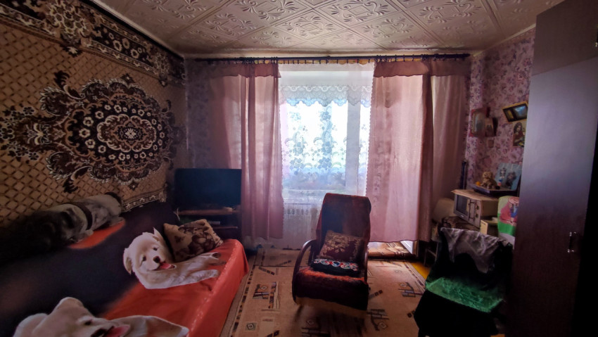 Жилая комната с ковром на стене и креслом у окна