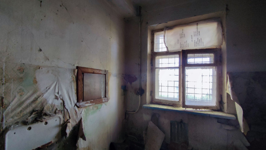 Комната с облупившимися стенами и старым окном