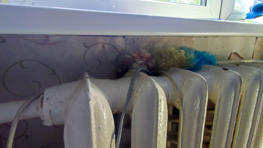 Чугунный радиатор под подоконником с предметами на фоне обоев