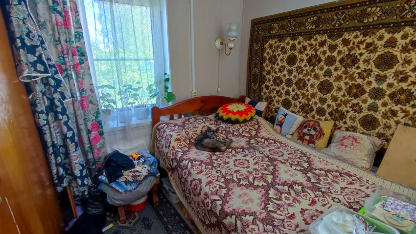 Кровать с узорчатым покрывалом и окном с текстильными шторами