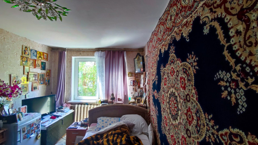 Жилая комната с настенным ковром, иконами и телевизором