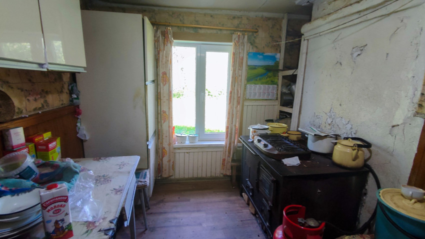 Кухонное помещение с холодильником, плитой и старой отделкой стен