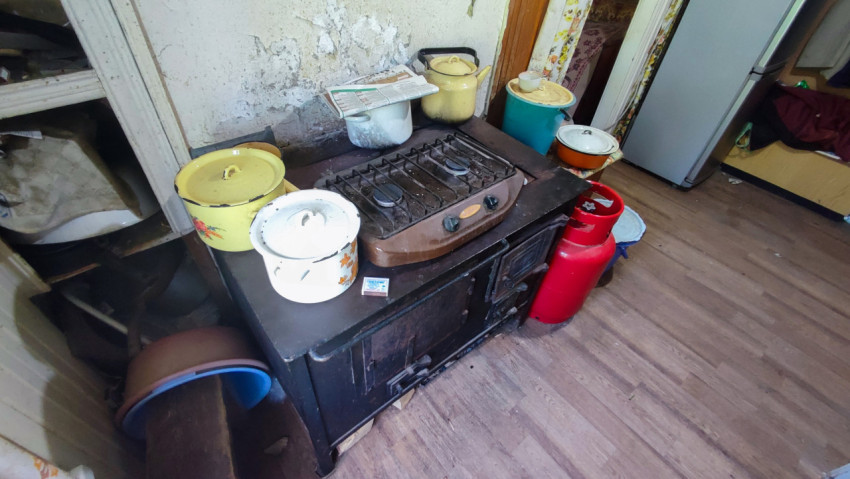 Плита с посудой и газовым баллоном в старой кухне