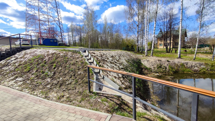 Берег водоёма с лестничным спуском и жилым домом на фоне