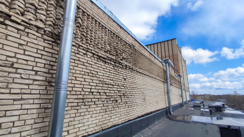 Кирпичная стена промышленного здания и технические элементы кровли