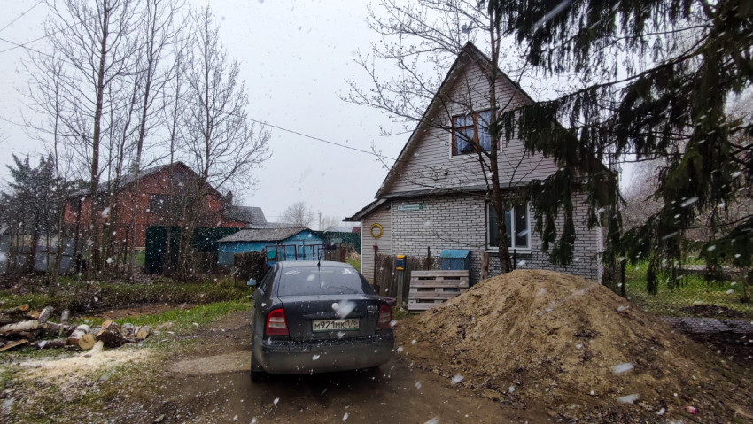 Деревянный дом и автомобиль во время снегопада