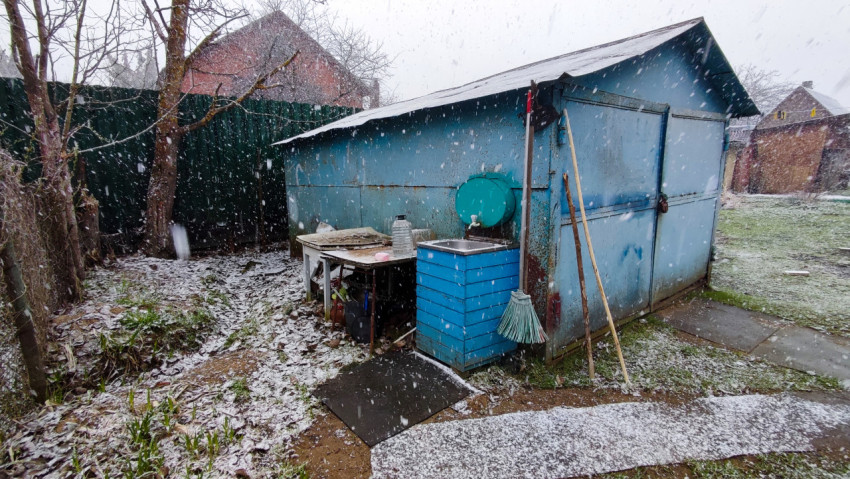 Хозяйственная постройка и уличная мойка во время снегопада