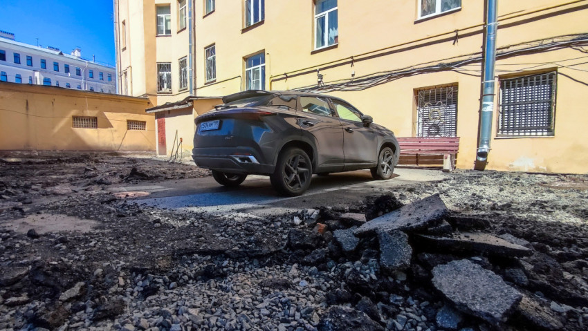 Автомобиль на площадке с разобранным асфальтом во дворе жилого дома