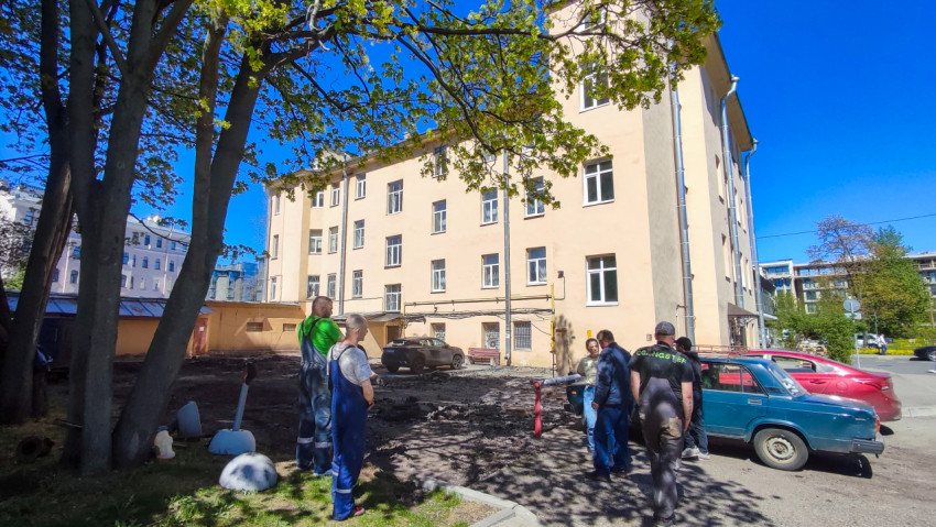 Рабочие обсуждают состояние двора возле жилого дома