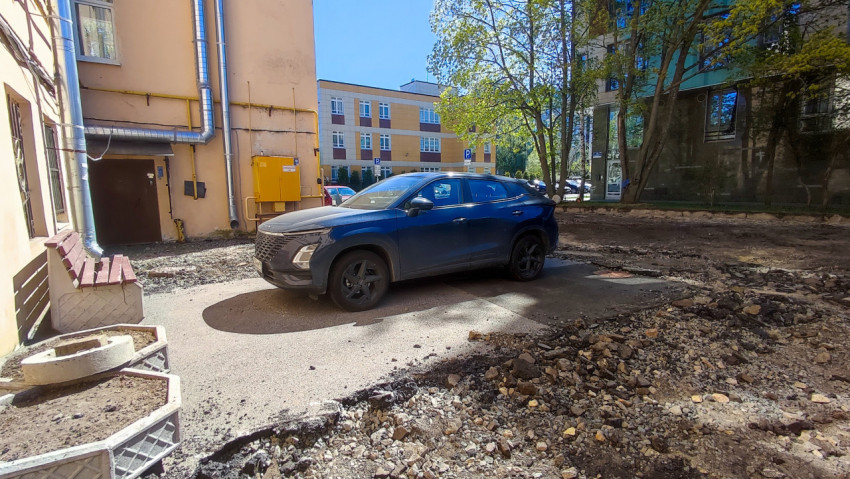 Автомобиль у подъезда жилого дома на фоне ремонтируемого двора