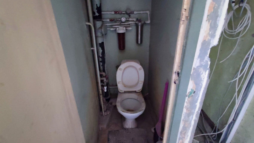 Комната с коммуникациями и старым санитарным оборудованием на этапе ремонта