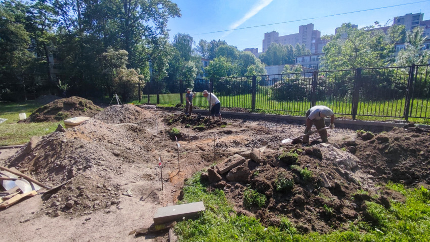 Рабочие проводят земляные работы на ограждённой территории парка