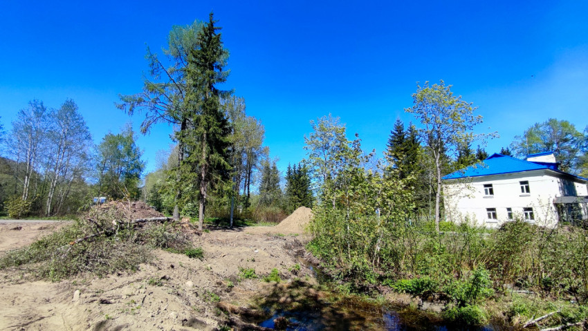Подготовленная территория с кучами веток и небольшим водоёмом